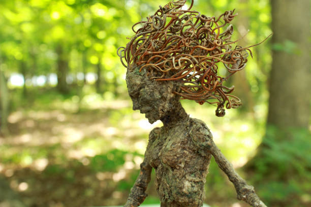 A mythical tree woman gazes down in front of a brightly lit forest background...